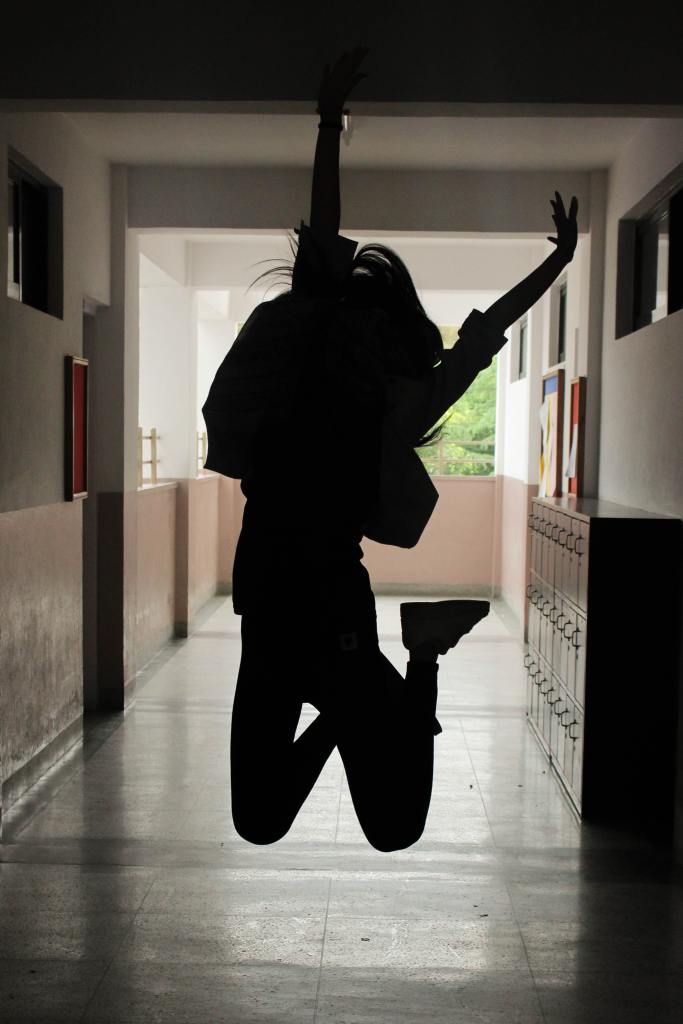 Student jumping in a school hallway.