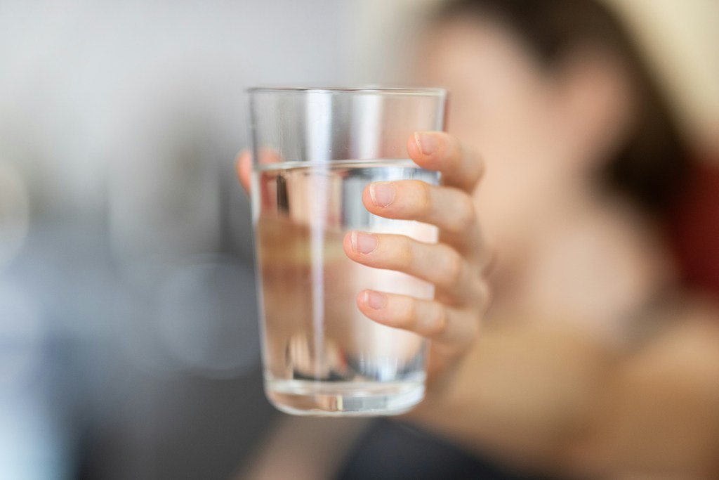 A hand holding a glass of clear water