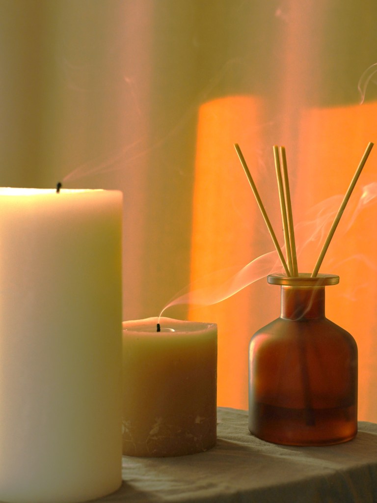 Candles and diffuser sticks sitting on a surface.